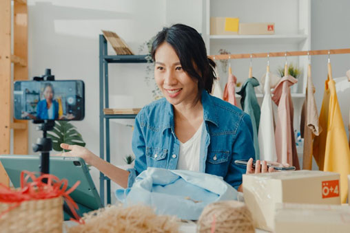 Mulher sorrindo em frente ao notebook , num atelier de moda